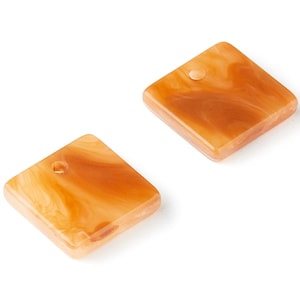 May include: Two square-shaped resin beads with a marbled brown and orange pattern. Each bead has a small hole in the center.