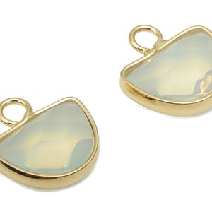 Può includere: Due ciondoli dorati a forma di mezza luna con una pietra trasparente e iridescente al centro. Ogni ciondolo ha un piccolo anello in cima per essere attaccato a gioielli.