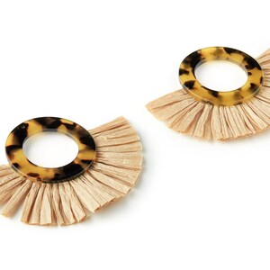 Puede incluir: Un par de pendientes de aro de carey marrón y negro con flecos de borla beige.