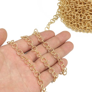 May include: A gold chain with a textured, twisted design. The chain is made of small, linked circles.