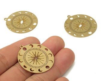 May include: Three gold-colored metal pendants with a celestial design. Each pendant is circular, featuring a sunburst pattern in the center and crescent moon cutouts around the edge. A small loop is at the top for hanging.