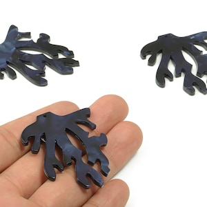 May include: Three dark blue coral-shaped pendants with a marbled effect. One pendant is held in a hand. The pendants have a hole at the top for stringing. These pendants are suitable for jewelry making and crafting.