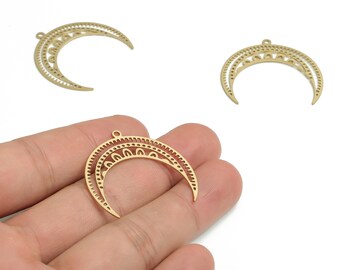 May include: Gold-colored crescent moon charms with intricate cut-out designs. The charms have a small loop at the top for attaching to jewelry. The image shows three charms, with one held in a hand.