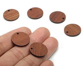 May include: A collection of round, wooden beads with a dark brown finish. Each bead has a small hole drilled near the edge. The beads are displayed on a white background, with some held in a hand.