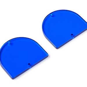 Puede incluir: Dos formas acrílicas de color azul semicirculares con bordes redondeados y un agujero en el centro de cada forma.