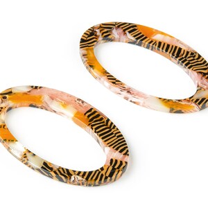 May include: Two oval-shaped, orange and black patterned hair clips.