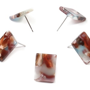 May include: Five rectangular stud earrings with silver posts. The earrings have a marbled appearance with shades of red, brown, white, and blue. The earrings are set against a white background.