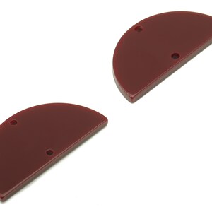 Puede incluir: Dos formas de acrílico de media luna de color marrón con dos agujeros cada una.