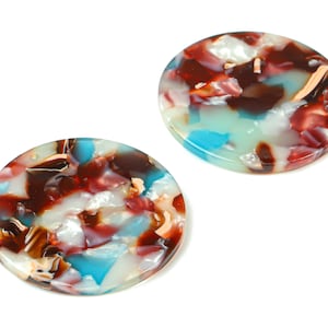 May include: Two round, colorful, decorative buttons with a marbled pattern in shades of brown, white, blue, and pink.