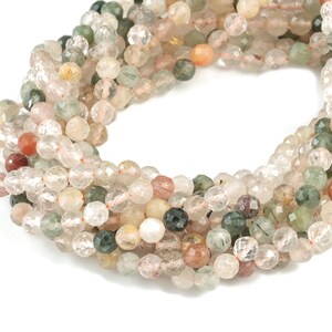 Peut inclure: Un brin de perles de pierres précieuses facettées dans des tons clairs, roses, verts et bruns. Les perles sont rondes et ont une forme légèrement irrégulière.