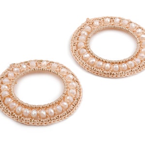 May include: A pair of gold hoop earrings with a beaded design. The beads are a light cream color and are evenly spaced around the hoop.