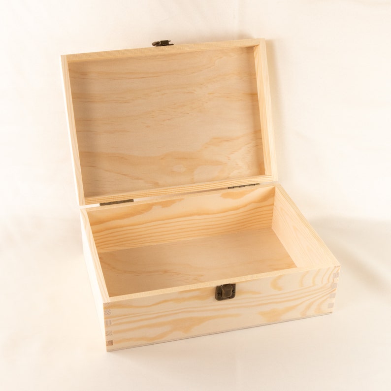 May include: An empty wooden box with a hinged lid and a brass latch. The box is made of light-colored wood and has a natural finish.
