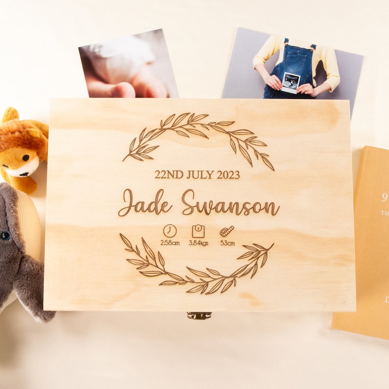 May include: A wooden keepsake box with an engraved inscription that reads "22nd July 2023 Jade Swanson 2.58cm 3.84kgs 53cm". The inscription is surrounded by a floral design.