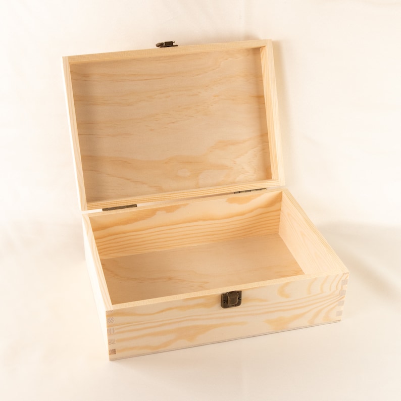 May include: An empty wooden box with a hinged lid and a brass latch. The box is made of light-colored wood and has a natural finish.