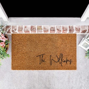 Custom natural coir door mat printed the family in black cursive texts