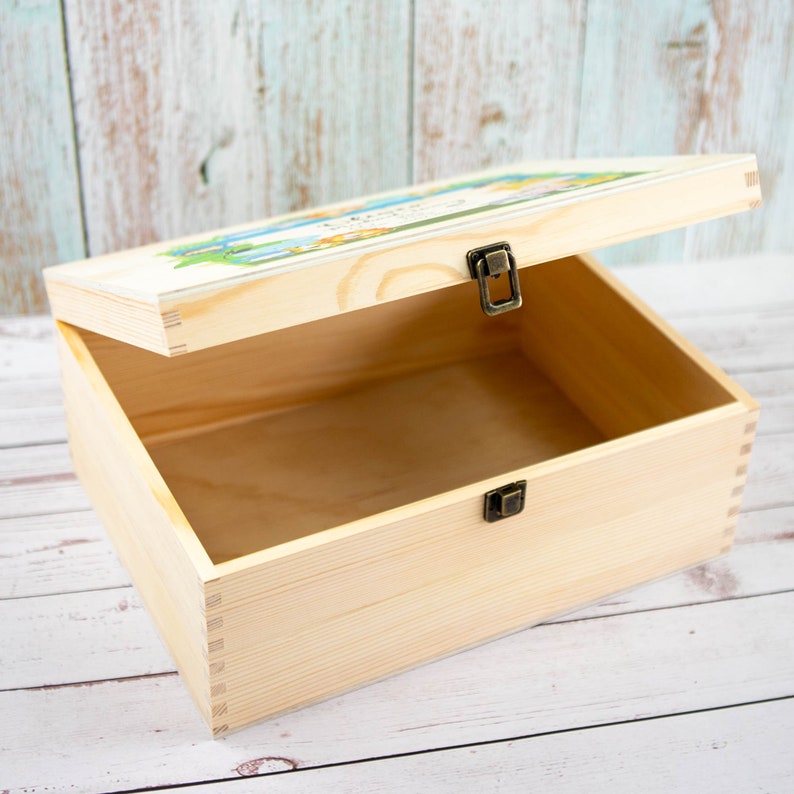 May include: A wooden box with a hinged lid and brass clasps. The lid is decorated with a colorful illustration of a woodland scene. The box is open and empty.