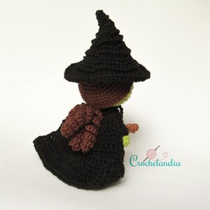 May include: A handmade crochet witch doll, featuring a black pointed hat and matching cloak. The doll has a brown head, a green face, and a brown and orange broom. The doll is a whimsical, handcrafted item.