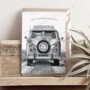 May include: A black and white greeting card featuring a detailed illustration of a vintage camper van on a dirt path. The van has a spare tyre mounted on the front and the text "HERE'S TO NEW ADVENTURES AHEAD!" printed in an arch above the vehicle.