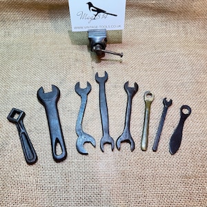 May include: A collection of ten vintage wrenches, including open-end wrenches, box wrenches, and a wrench with a square head. The wrenches are made of metal and have a dark gray finish.