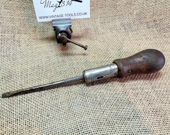 May include: A vintage screwdriver with a wooden handle and a metal shaft. The screwdriver has a keyhole on the side and the text "VICTOR" is visible on the shaft.