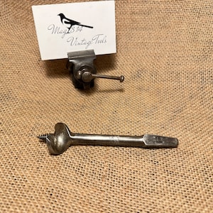 Puede incluir: Una broca de metal plateado con punta de tornillo y extremo plano. La broca está marcada con "5/8".