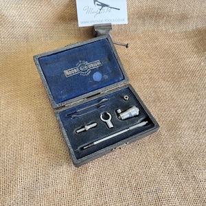 May include: A vintage wooden tool case with a blue velvet interior, containing small silver tools. The case is labelled "MOORE & WRIGHT" and is open, revealing a micrometer and other precision instruments. The case rests on a hessian surface.