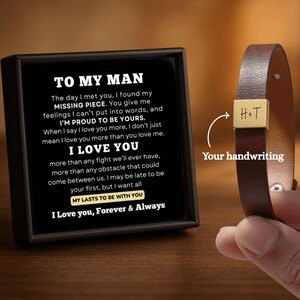 Può includere: Un braccialetto in pelle marrone con una chiusura rettangolare color oro incisa con le iniziali "H+T". Il braccialetto è esposto accanto a una carta incorniciata nera con il testo "TO MY MAN" e un messaggio romantico.