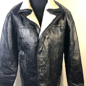 May include: A black leather jacket with a shearling collar. The jacket has a quilted design and multiple buttons.