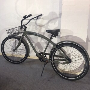 May include: A green cruiser bicycle with black components, including a basket, seat, and tyres with white sidewalls. The bike has a curved frame and mudguards. The text "paul frank" is visible on the frame.