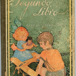 May include: A vintage children's book titled "Segundo Libro" with a green cover and illustrations. The cover shows a girl in a blue dress holding a doll and a boy in an orange shirt. The book has a distressed, aged appearance.
