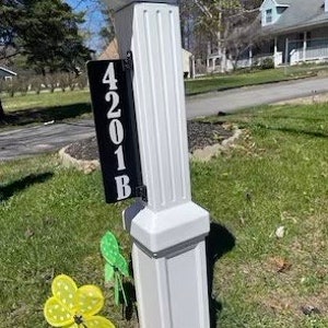 May include: Black and white house number sign with the number 4201B on a white post. The sign is mounted on the post with screws.