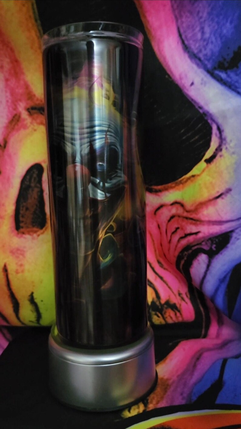 May include: A stainless steel tumbler with a black and white image of a clown with a red nose. The tumbler has a silver base and is sitting on a colorful background.