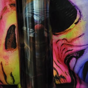 May include: A stainless steel tumbler with a black and white image of a clown with a red nose. The tumbler has a silver base.