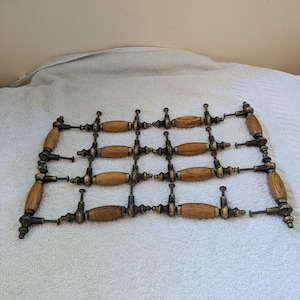 Puede incluir: Un juego de doce pomos de armario antiguos con acabado de madera y latón. Los pomos son de forma ovalada con un diseño decorativo en la madera.