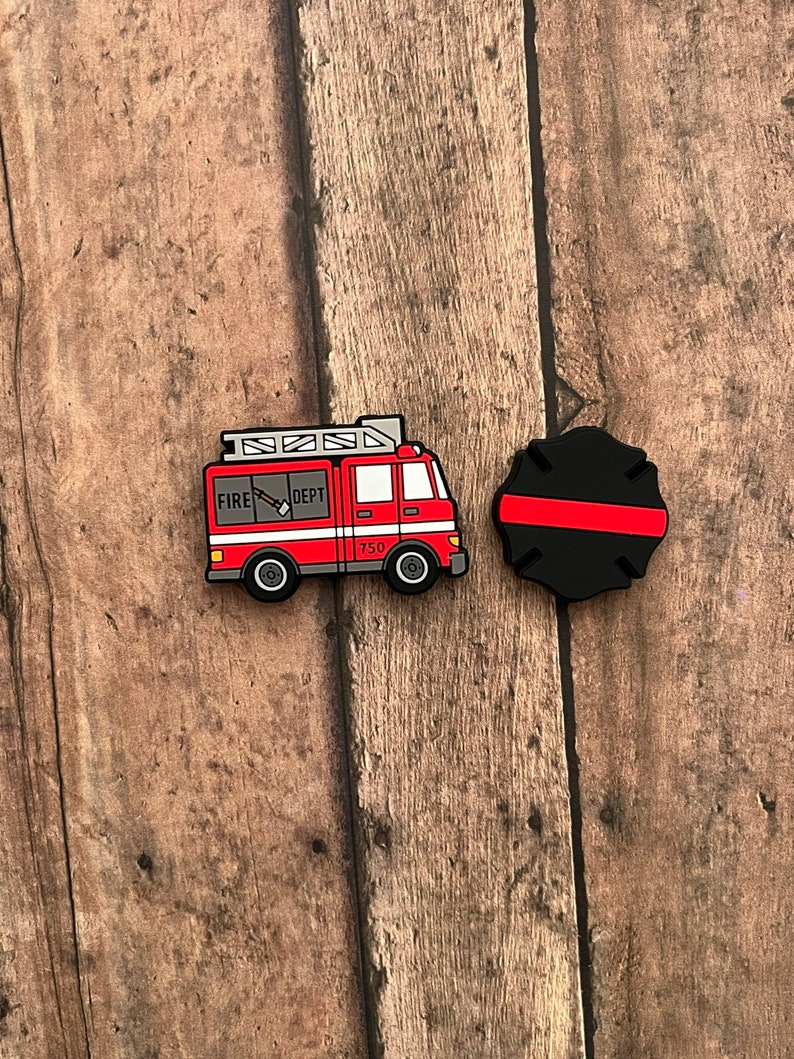 May include: Red and white fire truck with the words "FIRE DEPT" and "750" on the side. The truck is next to a black and red fire hat.