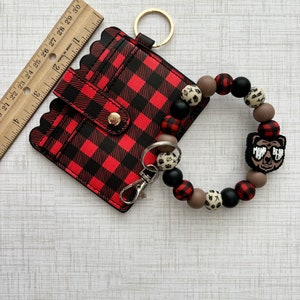 May include: Red and black buffalo check card holder with a gold key ring and a brown, black and white beaded wristlet with a "Mom Bear" charm.