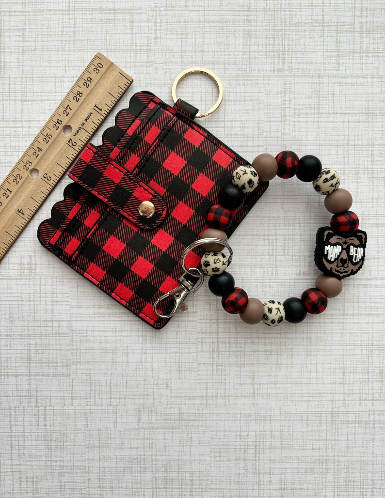 May include: Red and black buffalo check card holder with a gold key ring and a brown, black and white beaded wristlet with a "Mom Bear" charm.
