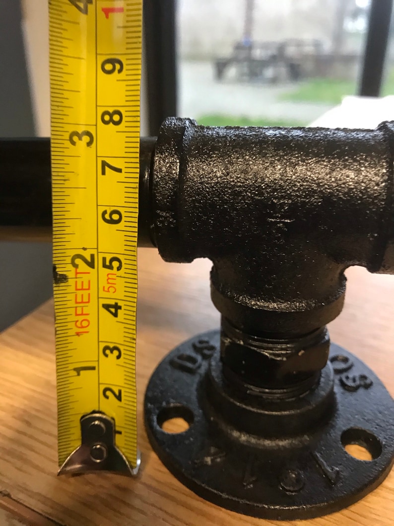 May include: Black metal pipe fitting with a flange and a measurement tape showing 3 inches. The pipe fitting is used for plumbing or industrial applications.