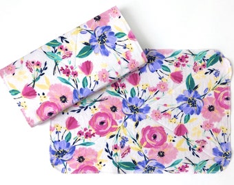 May include: Two white cotton dishcloths with a floral pattern. The pattern features pink, yellow, and purple flowers on a white background.