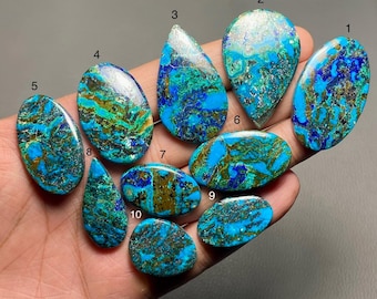 Könnte beinhalten: Zehn türkisfarbene Cabochons mit goldenen und silbernen Einschlüssen. Die Cabochons haben verschiedene Formen und Größen, darunter ovale, tropfenförmige und runde.
