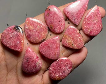 May include: Nine pink and white rhodochrosite cabochons of various shapes and sizes, numbered 1 through 9.