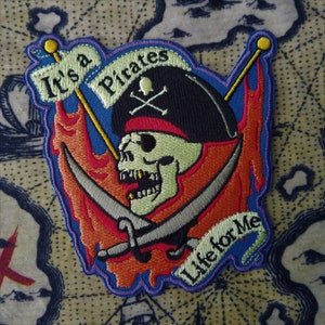 May include: Embroidered pirate patch featuring a skull wearing a tricorn hat with crossed bones. The patch includes the phrases "It's a Pirates" and "Life for Me" with a map background. The design incorporates red, orange, blue, and green colors.