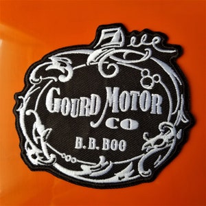 May include: Black and white embroidered patch with a stylized design of a gourd with the text "Gourd Motor Co. B.B. Boo" inside.