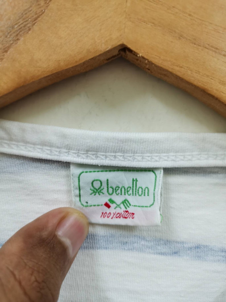 May include: White striped t-shirt with a green and white Benetton label. The label says "100% cotton".