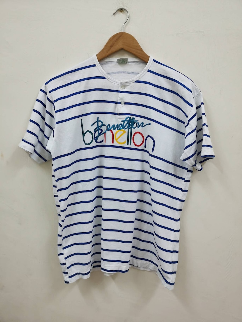 May include: White and blue striped t-shirt with a colorful Benetton logo.