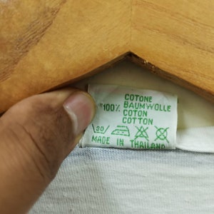 May include: A white and blue striped t-shirt with a green care label that reads "Cotone, Baumwolle, Coton, Cotton, 100%, Made in Thailand".