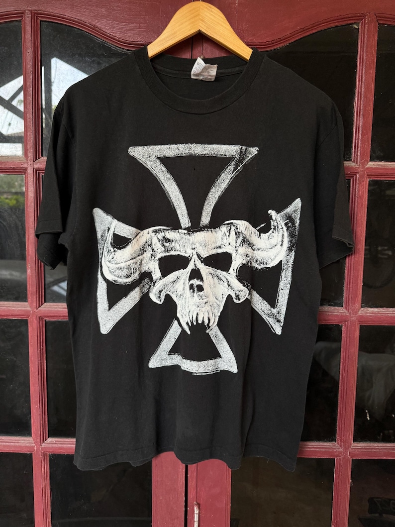 May include: Black t-shirt featuring a white skull and crossbones design. The skull has horns and a fierce expression.