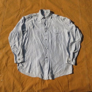 May include: A light blue long-sleeved button-down shirt with a single pocket on the left chest.