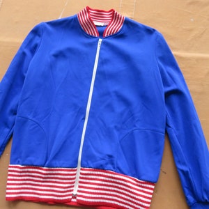 May include: A blue zippered jacket with red and white striped trim around the collar and bottom hem.