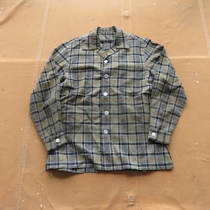 Può includere: Una camicia a maniche lunghe a quadri con colletto abbottonato. La camicia è un mix di quadri verdi e neri.